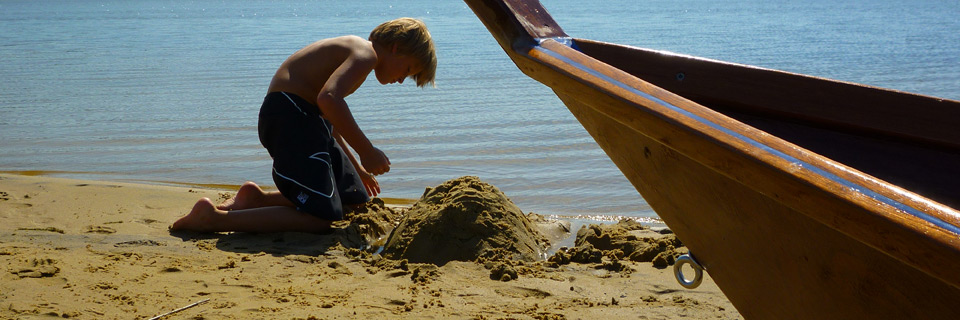 enfant sur la plage avec pirogue long tail en contre plaque marine resine epoxy